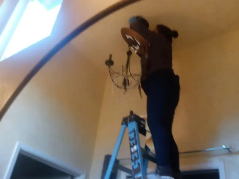 Electrician installing a chandelier in a Hondo residence